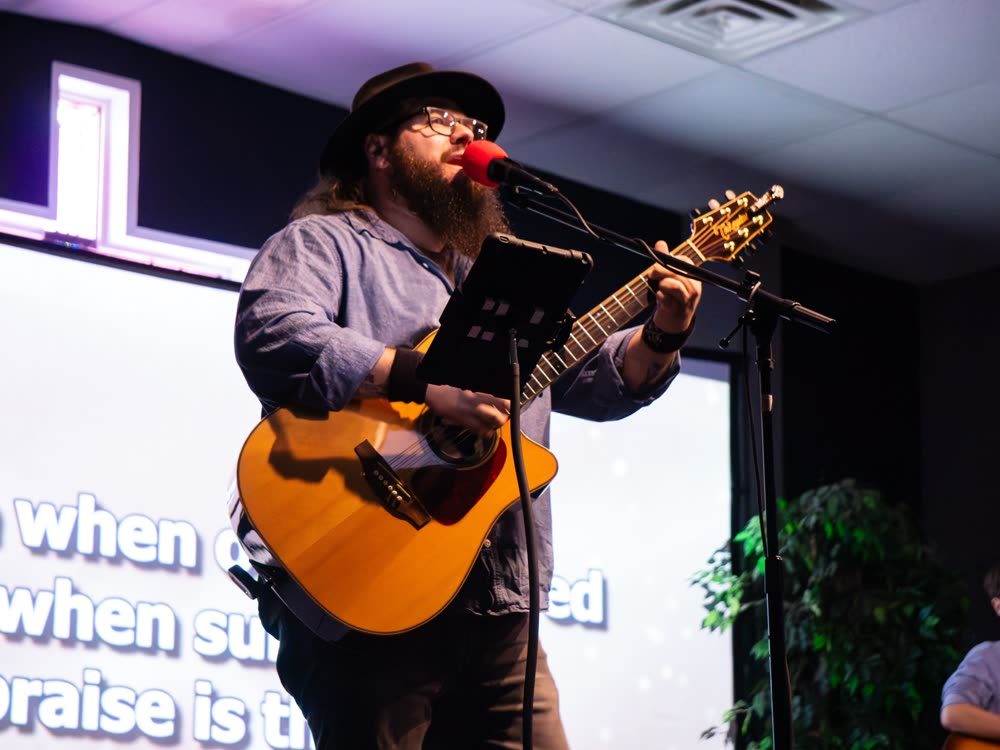 A worship leader singing with song lyrics on the screen behind