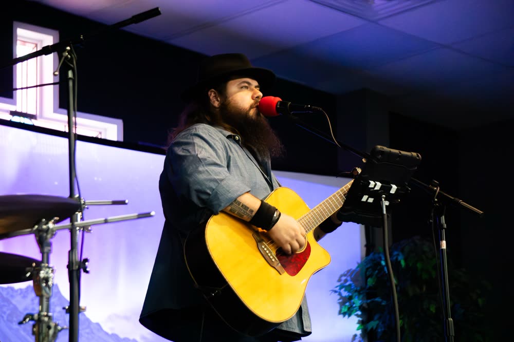 A worship leader singing and playing acoustic guitar
